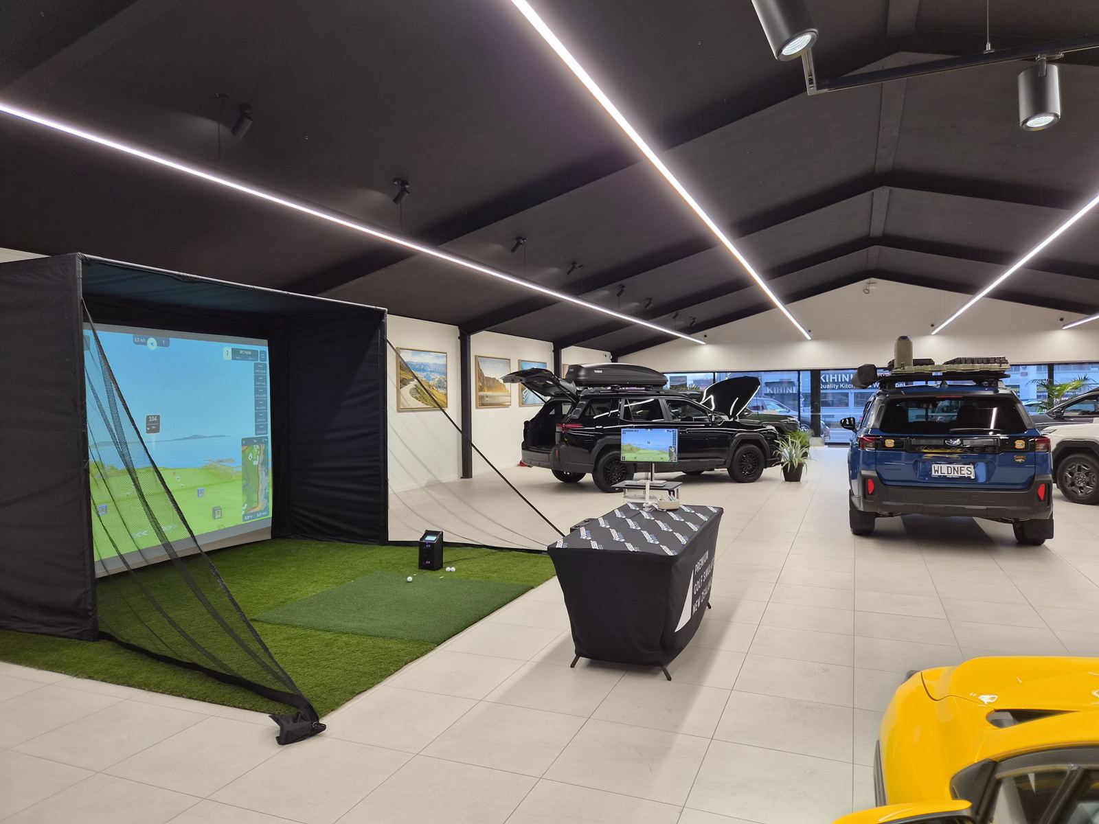 The SIM-ON golf simulator set up inside a car showroom beside a branded stand