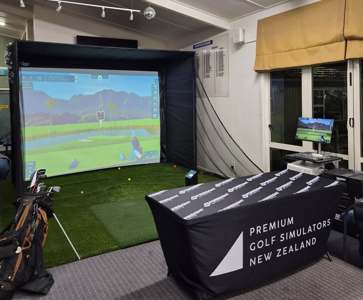 The simulator set up indoors with its enclosure, screen, hitting mat, launch monitor and a bag of clubs ready to use
